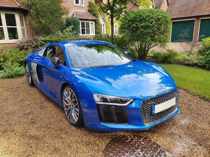 Blue Audi R8 on a gravel driveway after a valet, seen from the front corner