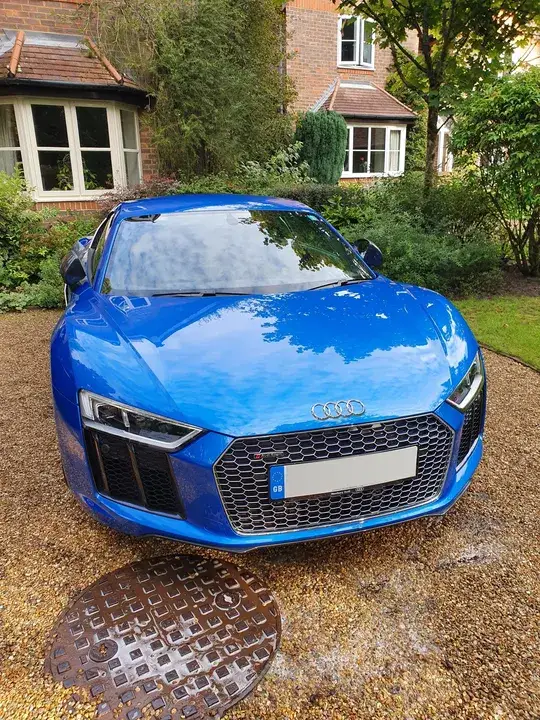 Front of a freshly valeted blue Audi R8 with the bonnet reflecting the trees