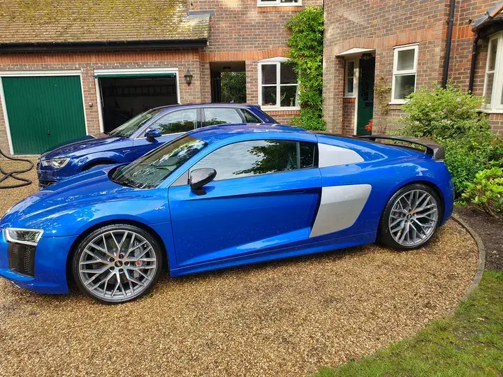 Side view of a valeted blue Audi R8 parked in front of a blue Audi hatchback