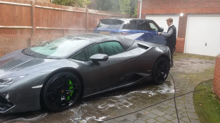Our valeter pressure washing a grey Lamborghini Huracán Spyder on the customer's driveway