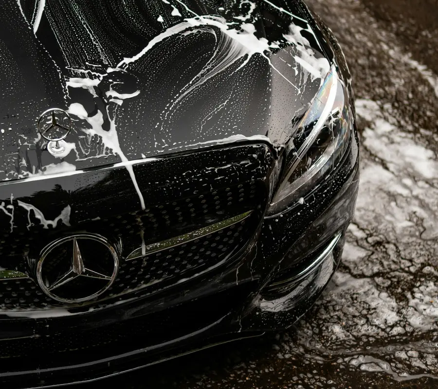 Black car bonnet covered in snow foam during a hand wash