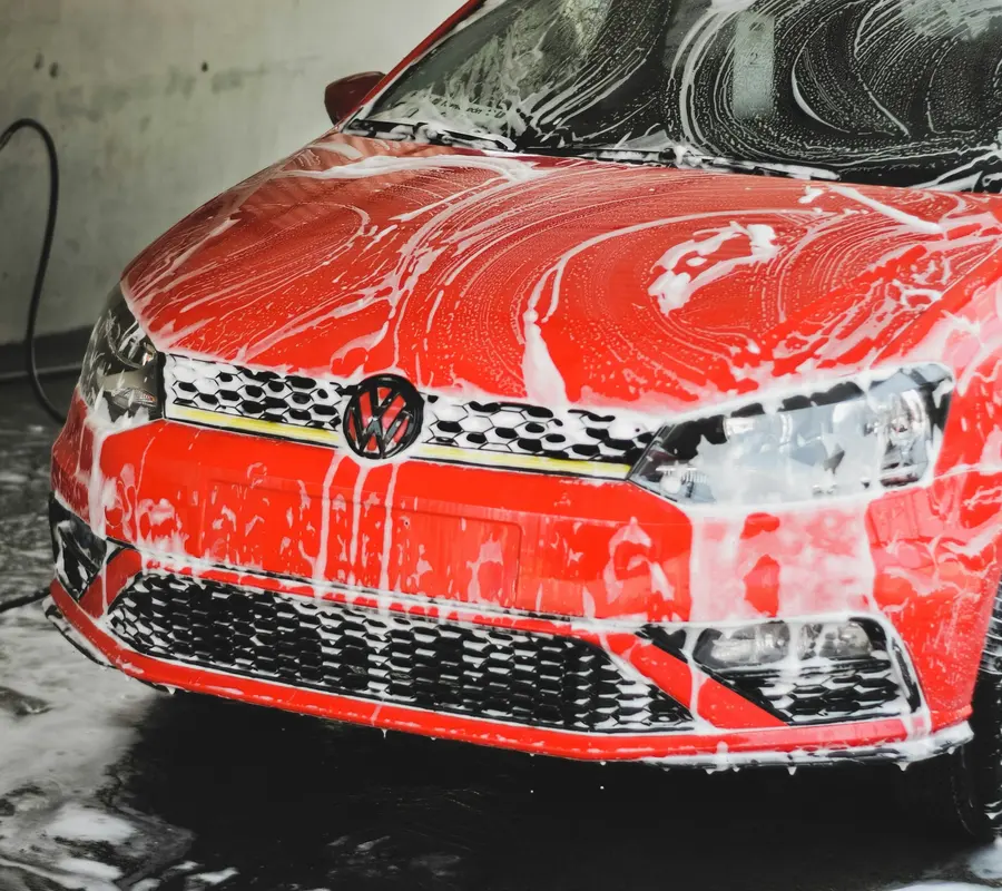 Red hatchback covered in snow foam