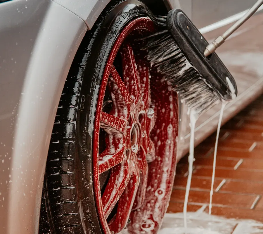 Alloy wheel being scrubbed with a brush and soapy water